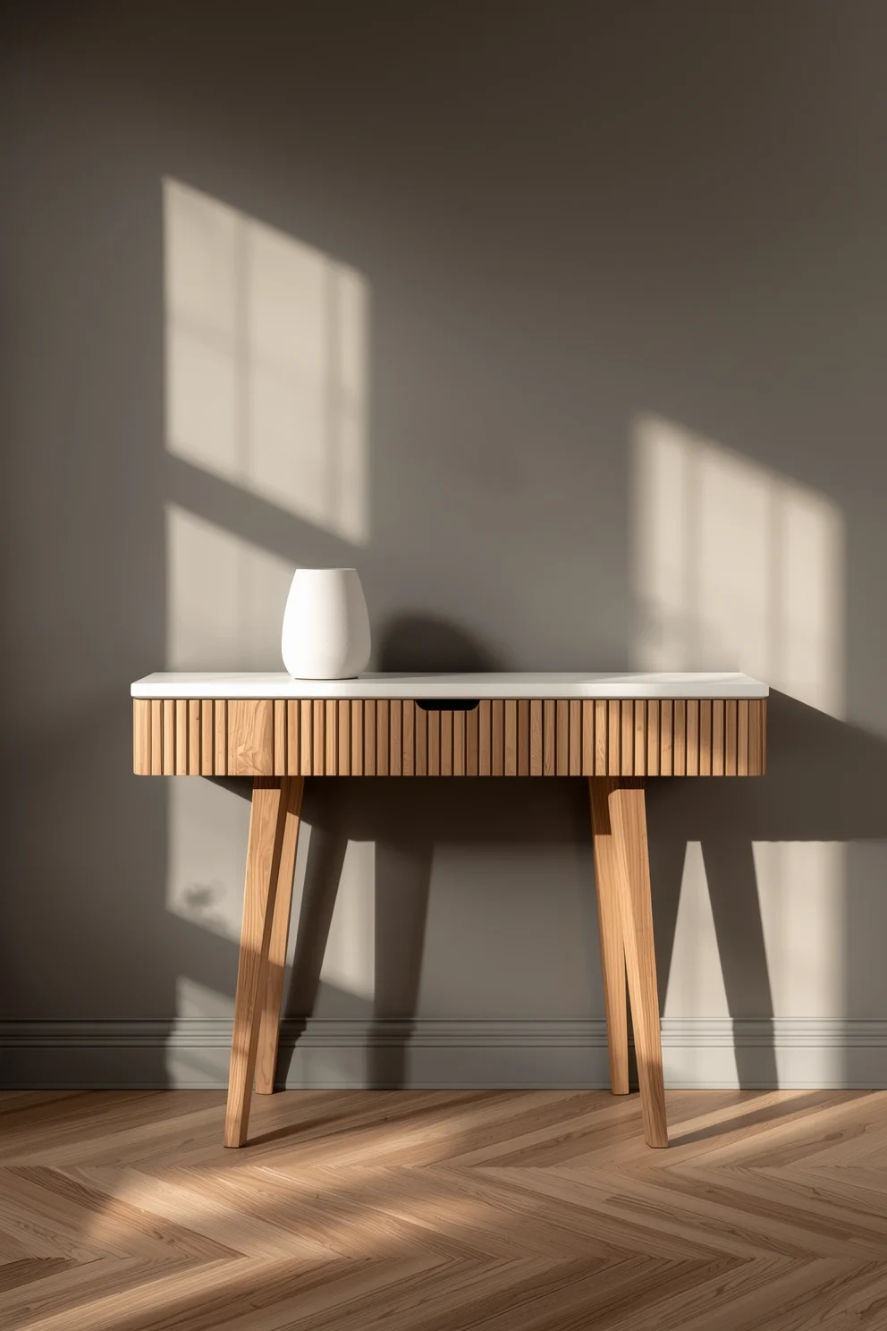 Console murale en bois clair avec pieds obliques et plateau blanc rainuré, vase blanc minimaliste sur mur gris taupe.