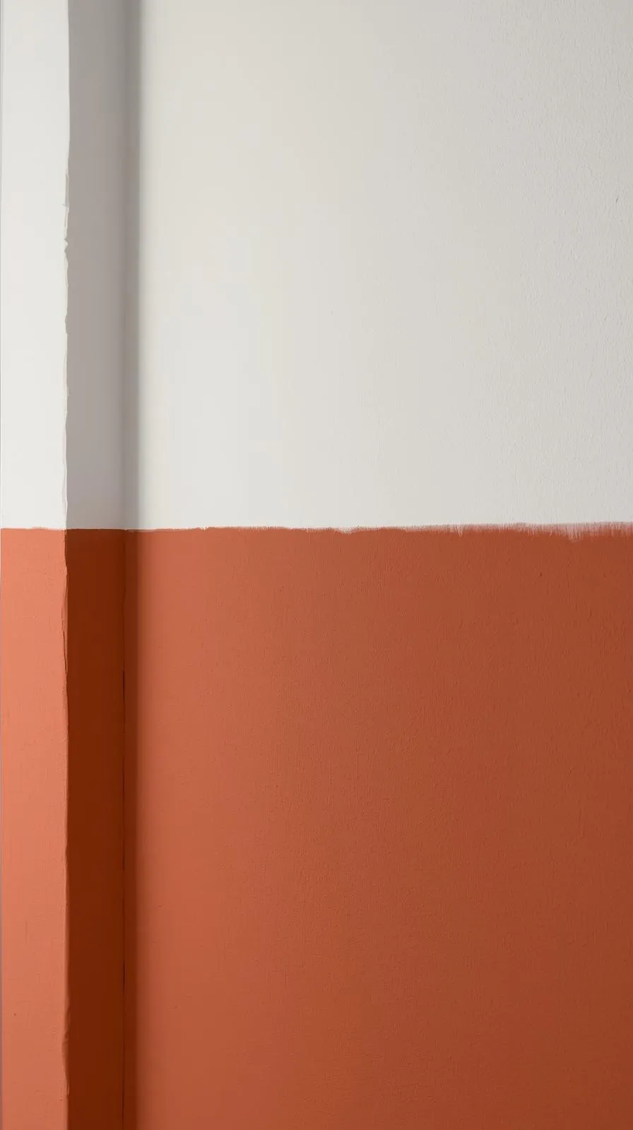Un mur de couloir peint en deux tons : blanc en haut et une large bande de couleur terracotta en bas, créant un soubassement horizontal.
