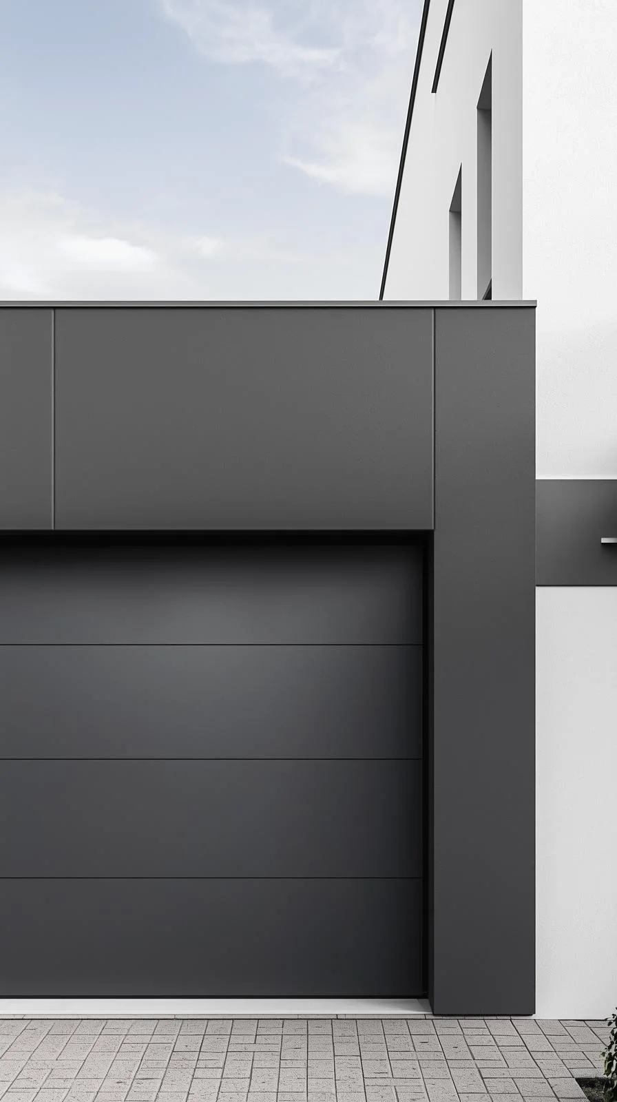 Une façade de maison moderne avec un mur d'accent gris anthracite autour de la porte de garage, contrastant avec le mur blanc du reste de la maison.