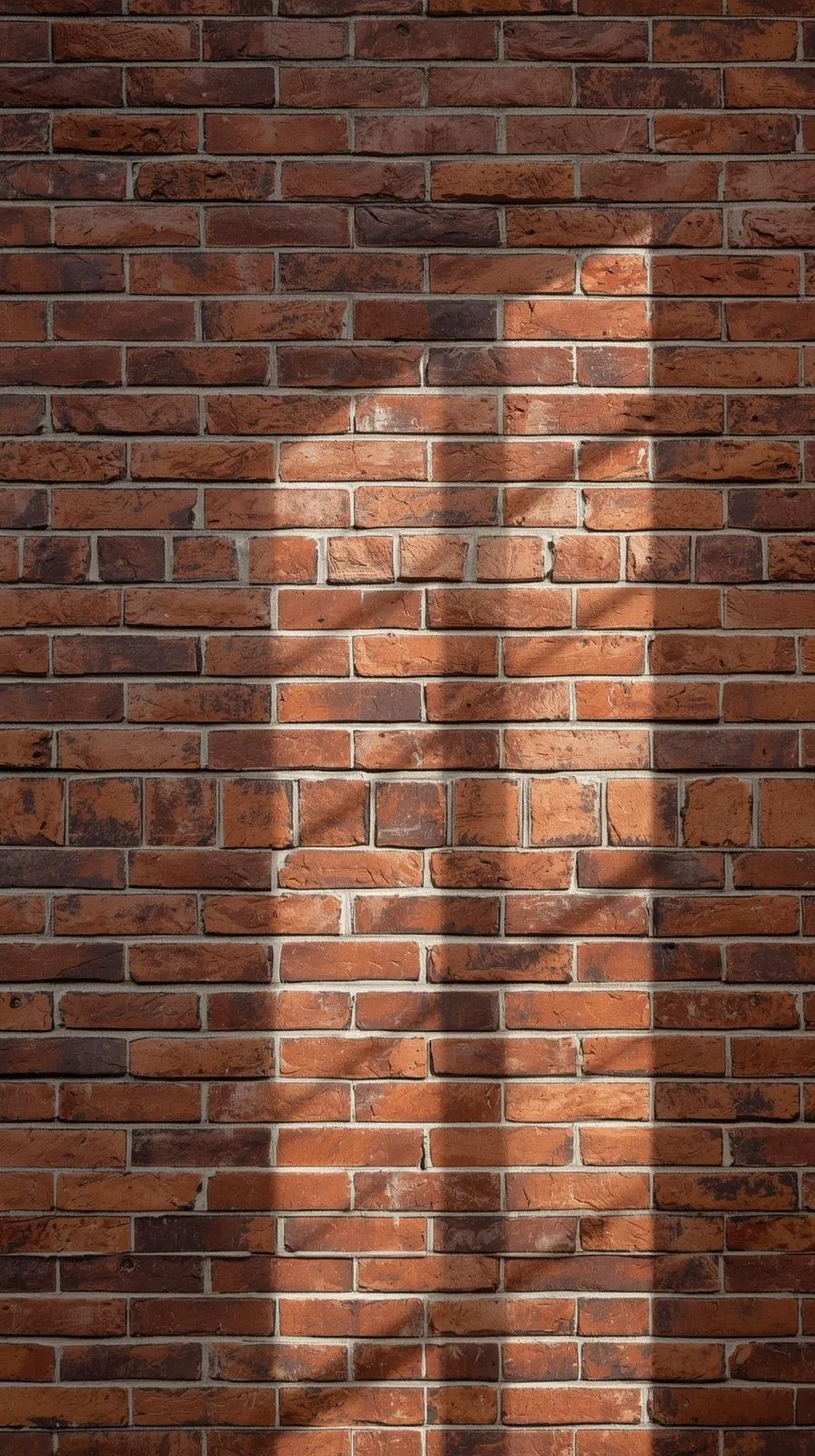 Gros plan sur une tapisserie en trompe-l'œil imitant un mur de briques rouges réaliste, éclairé par le soleil.