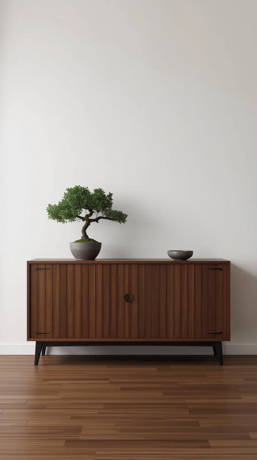 Un buffet d'entrée bas en bois sombre de style japonais, avec des portes coulissantes et un bonsaï posé dessus pour une ambiance zen.