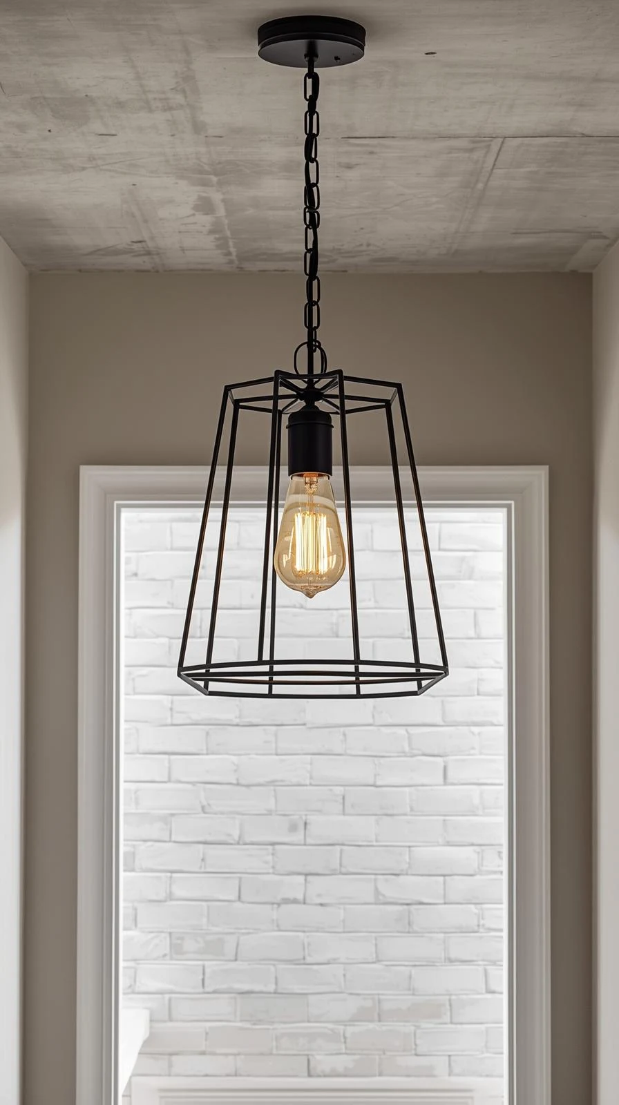 Un lustre cage en métal noir mat de style industriel, avec une ampoule Edison vintage, suspendu dans une entrée.